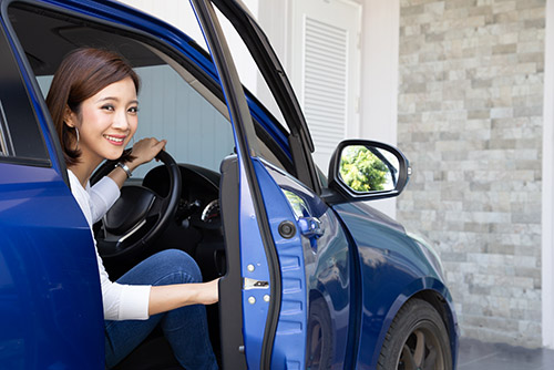 Young Asian woman getting out of a car or open door car after parking in front of the house